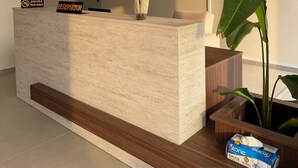 Un mostrador de recepción con un letrero, una orquídea en maceta y una planta grande.