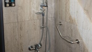 Una ducha con cabezal de ducha de mano, un accesorio de ducha manual y un cabezal de ducha fijo en la pared.