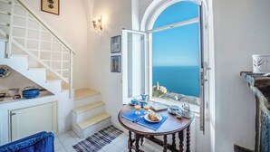 A room with a staircase, a dining table with breakfast items, and a view of the sea. - Casa Capo di Conca by Wonder Tour (Conca dei Marini)