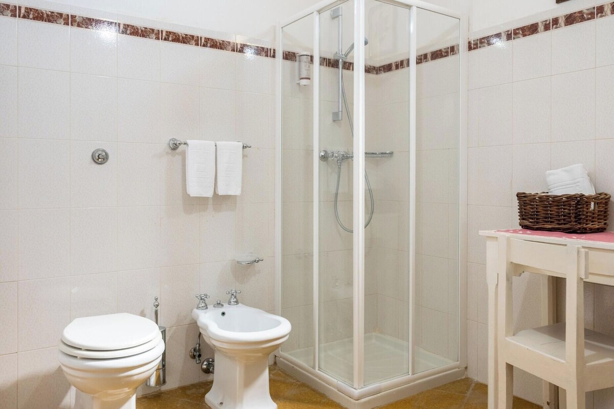 A bathroom with a toilet, bidet, and glass-enclosed shower.