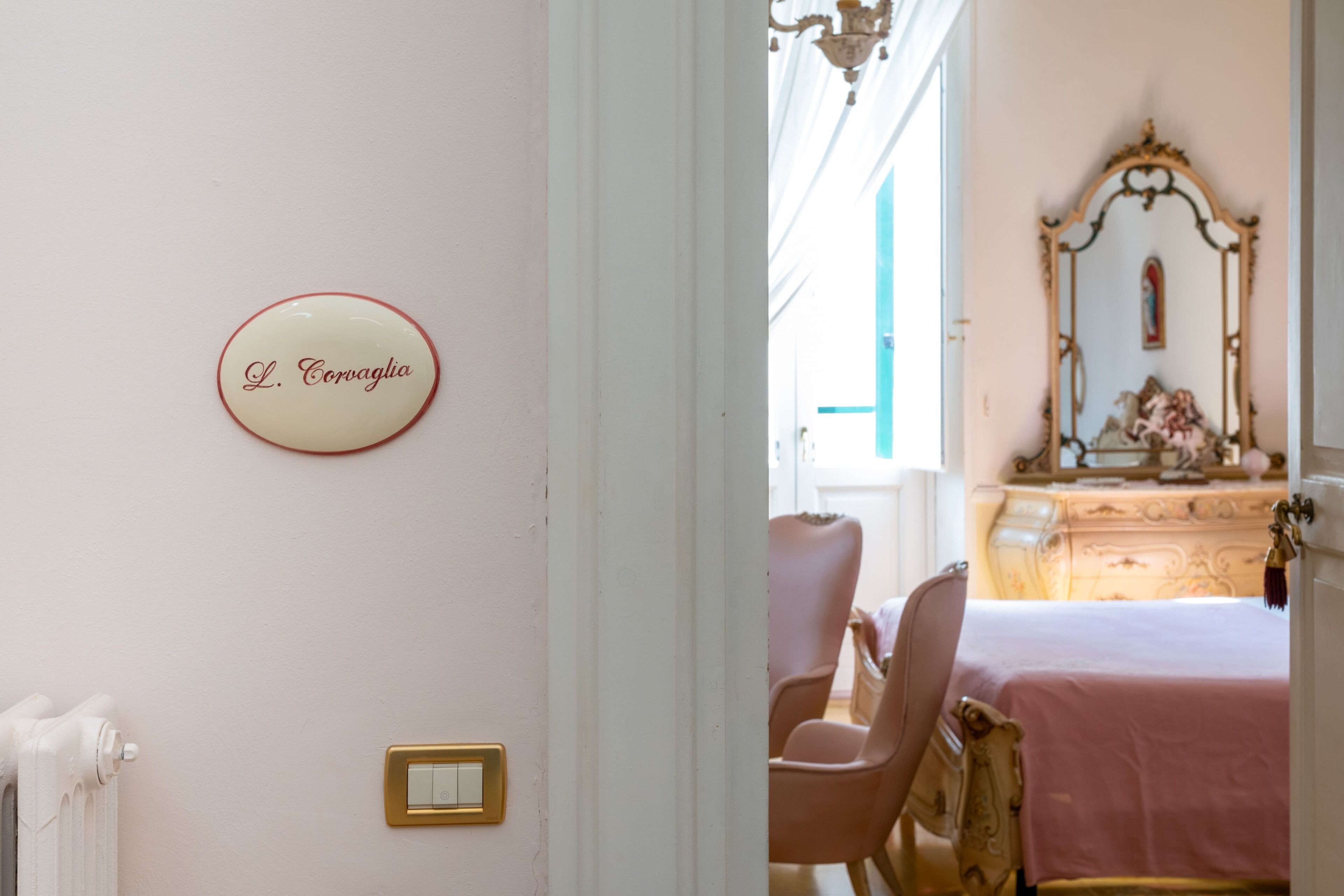 A room with a bed, a dresser, a chair, a mirror, a light switch, and a sign on the wall.