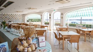 Un restaurante con barra de buffet, mesas, sillas y vistas a través de amplios ventanales.