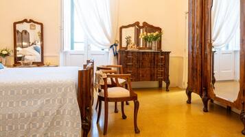 Ein Zimmer mit einem Bett, einem Holzkommode, Stühlen und einem großen Spiegel.