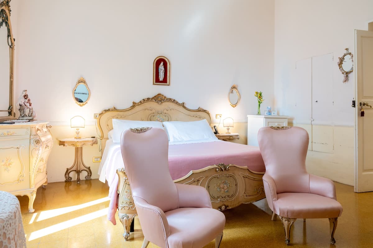 Une chambre à coucher avec un lit, deux chaises, une commode et un miroir.