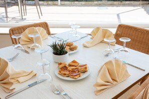 A dining table set with plates of food, wine glasses, cutlery, and a small potted plant. - Hotiday Leuca Porto (Santa Maria di Leuca)
