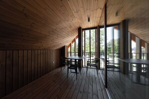 A wooden interior with a high ceiling, large windows, and a table with chairs. - Boutique Hotel Sončno Polje (Moravske Toplice)