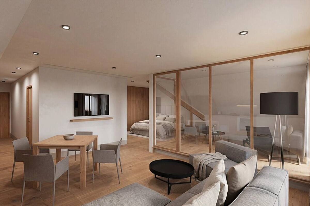 A modern living room with a wooden dining table, grey sofas, a black coffee table, and a large mirror.