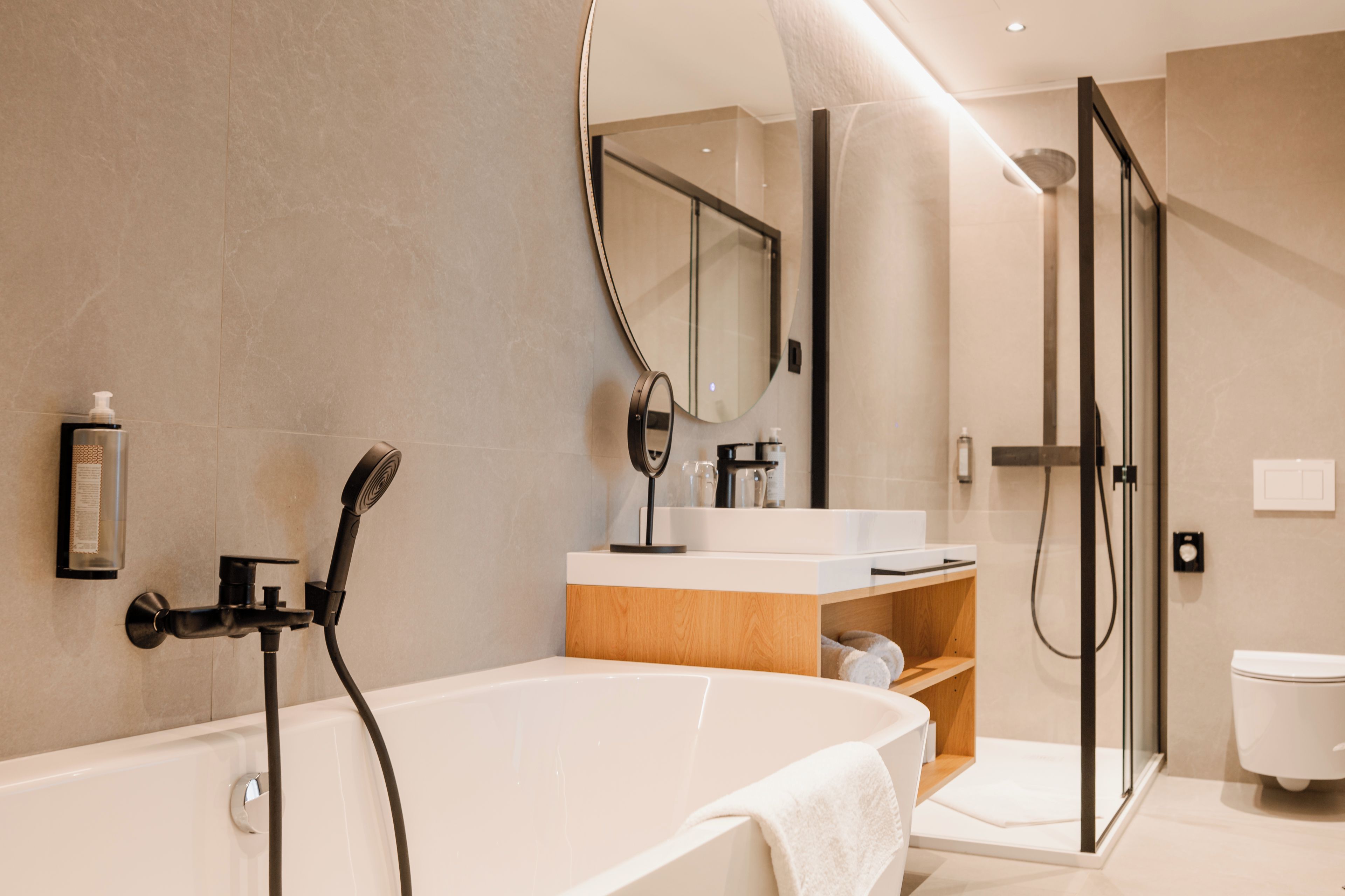 A modern bathroom with a freestanding bathtub, a glass-enclosed shower, and a vanity with a mirror.