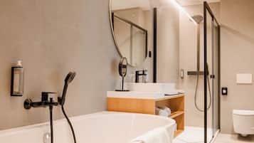 A modern bathroom with a freestanding bathtub, a glass-enclosed shower, and a vanity with a mirror.