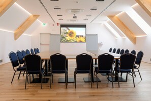 A conference room with a long table, chairs, a projector screen, and a large window. - Boutique Hotel Sončno Polje (Moravske Toplice)