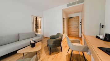 A modern living room with a grey sofa, two armchairs, a coffee table, and a wooden floor.