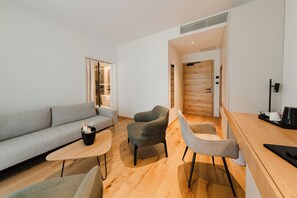 Una sala de estar moderna con un sofá gris, dos sillones, una mesa de centro y suelo de madera.