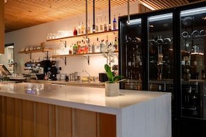 A bar area with a countertop, shelves with bottles, a coffee machine, and a refrigerator. - Boutique Hotel Sončno Polje (Moravske Toplice)