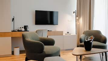 Uma sala de estar moderna com televisão de tela plana na parede, máquina de café e área de jantar com mesa e cadeiras.