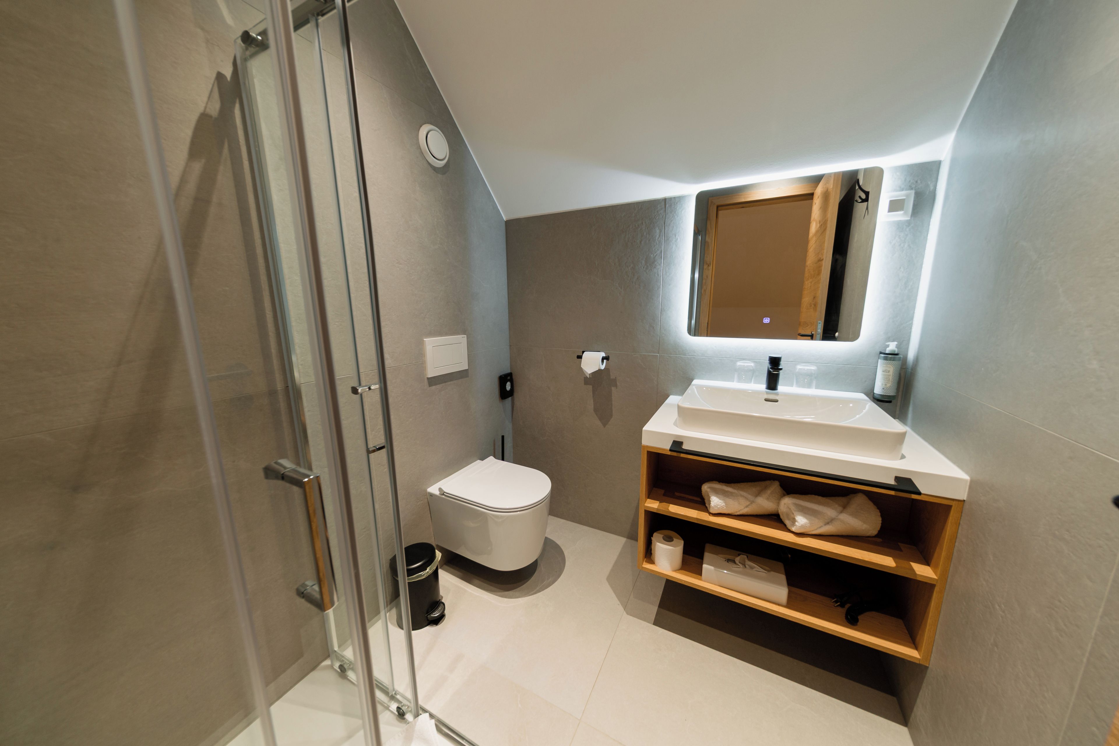 Un baño moderno con cabina de ducha de vidrio, inodoro blanco y tocador con espejo.