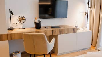 A modern hotel room with a wooden desk, a flat-screen TV, a chair, and a bed.
