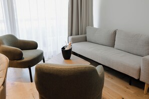 A modern living room with a grey sofa, two armchairs, and a coffee table. - Boutique Hotel Sončno Polje (Moravske Toplice)