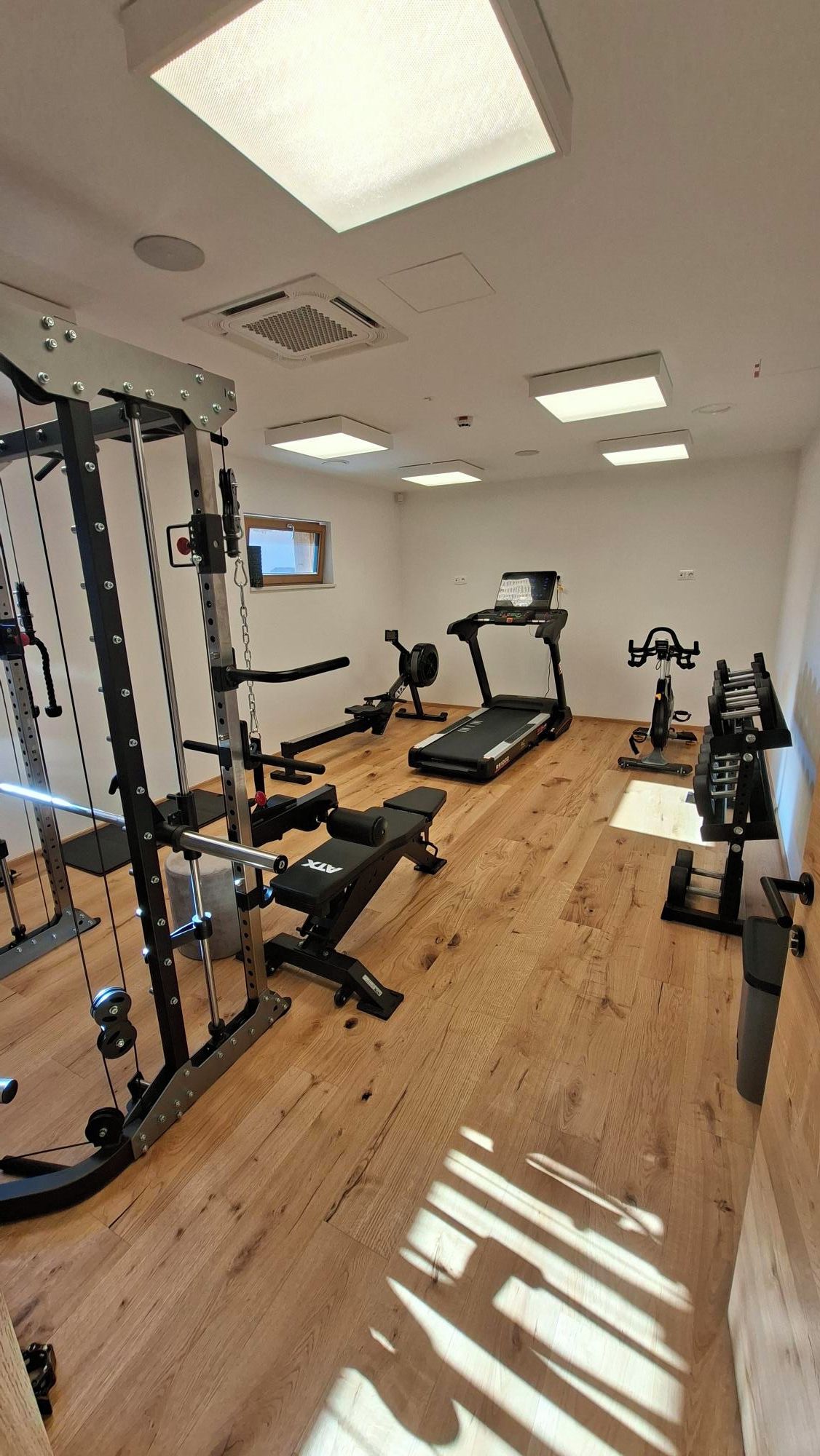 Un gimnasio con equipos de ejercicio variados, incluyendo una cinta de correr, bicicleta estática y máquinas de pesas.