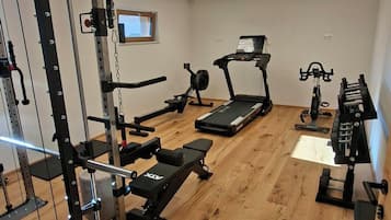 Un gimnasio con equipos de ejercicio variados, incluyendo una cinta de correr, bicicleta estática y máquinas de pesas.