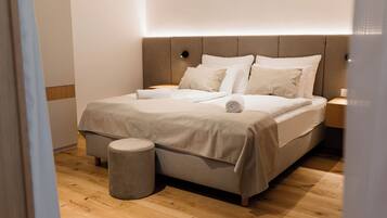 A modern bedroom with a bed, bedside tables, and a small stool.