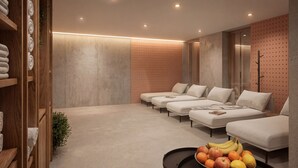 A modern spa room with a row of three white sofas, a wooden shelf with towels, and a bowl of fruit on the floor. - Boutique Hotel Sončno Polje (Moravske Toplice)