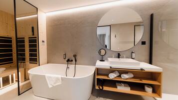 A modern bathroom with a freestanding bathtub, a vanity with a mirror, and a wooden shelf.