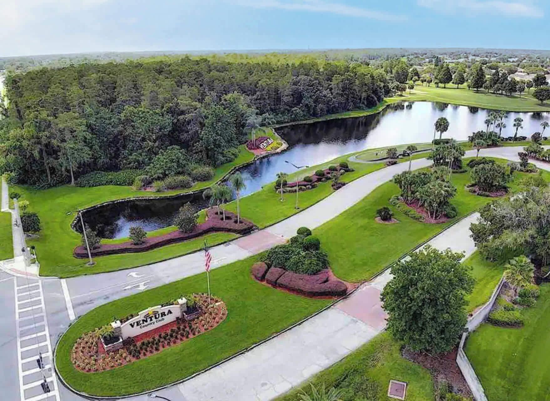 Ein Golfplatz mit Teich, umgeben von üppiger Vegetation und einem Fahnenmast mit der US-amerikanischen Flagge.