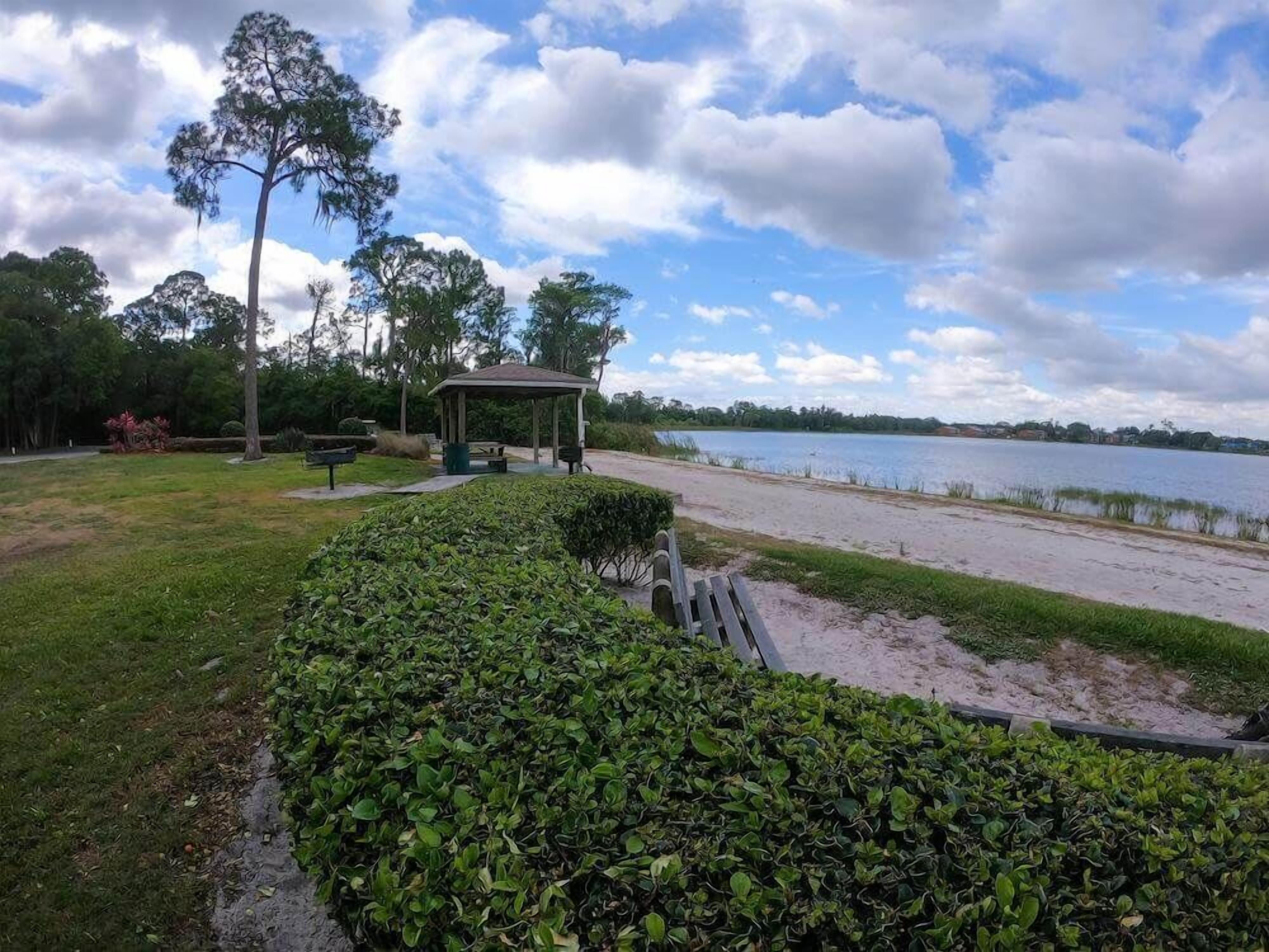 A park with a gazebo, a bench, and a lake.