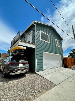 Ein zweistöckiges Haus mit Garage, Balkon und einem abgestellten SUV.