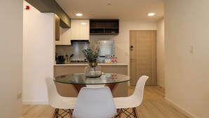 Una cocina moderna con armarios blancos, una mesa de comedor de vidrio y sillas blancas.
