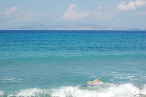 A coastal view with clear blue water, distant mountains, and a rocky outcrop. - Paradisi Sea Escape Near the Beach (Rhodes)