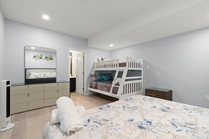 Une chambre à coucher avec un lit superposé, une table de chevet, un miroir et une armoire.