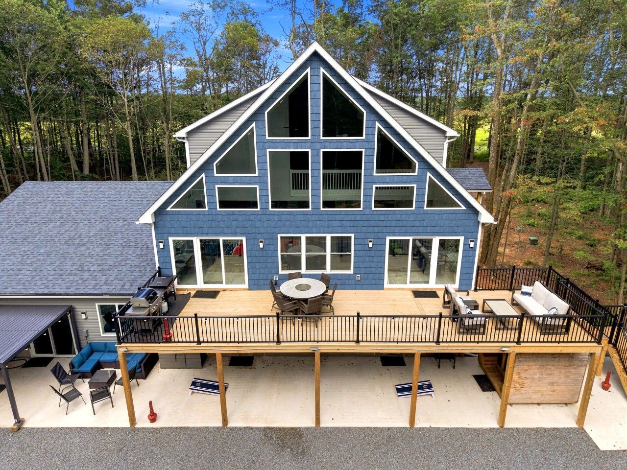 Une maison à deux étages dotée d’une terrasse, d’un espace salon extérieur et d’un garage.