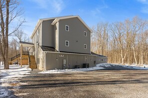 A two-story building with a covered entrance and a staircase leading to the main entrance. - 6 Masters, 8 Bath, Indoor Pool, Pickle Ball Ct, Hot tub, Sauna, Big Game Room (Long Pond)