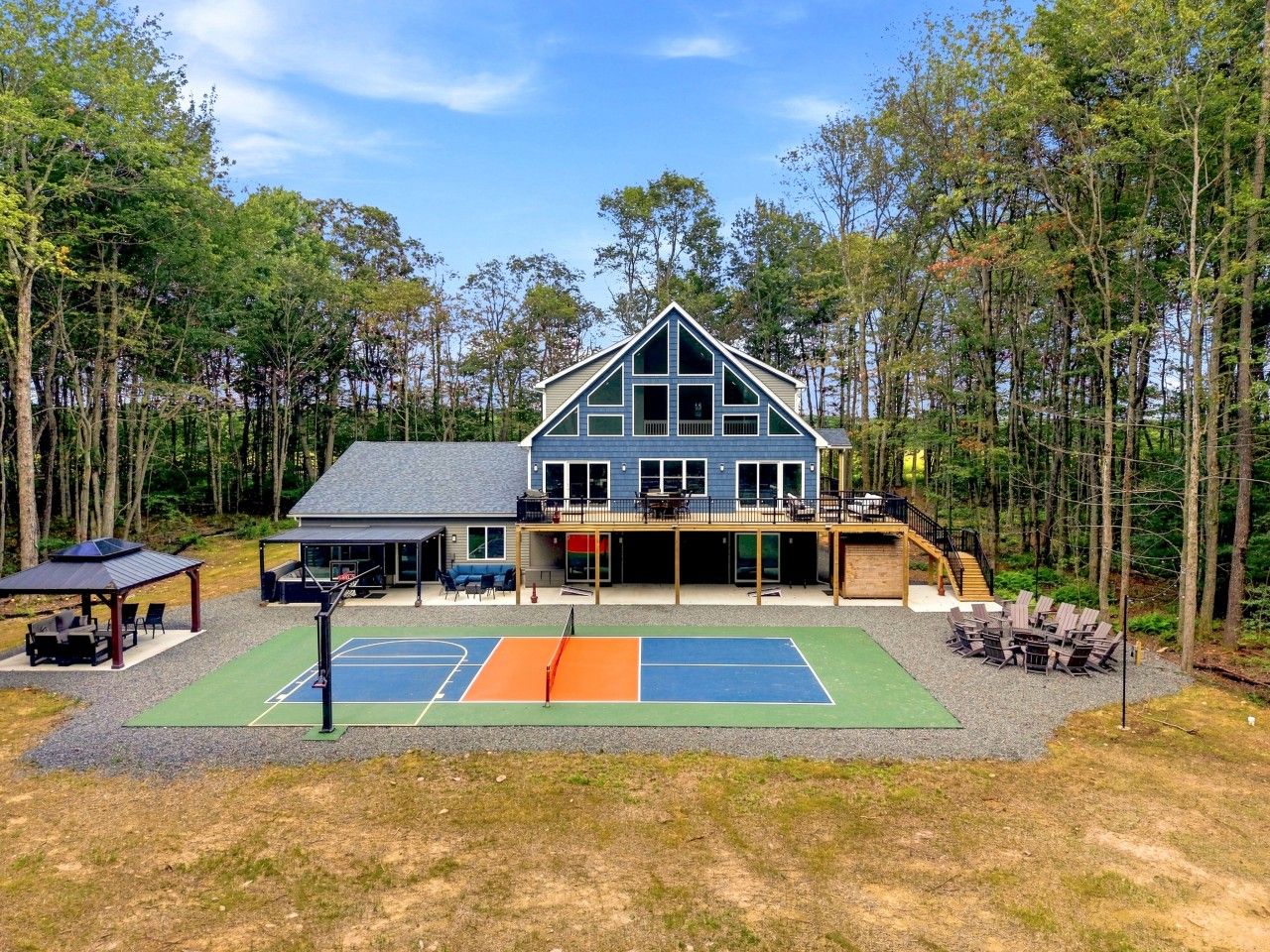 Une maison à deux étages avec un court de tennis à l  ’avant.