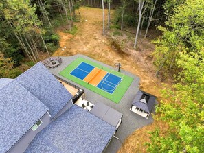 Ein Wohnanwesen mit einem zweigeschossigen Gebäude, einem Tennisplatz und einem kleinen Gartenhaus.