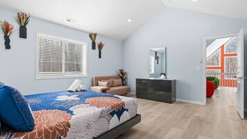 A modern bedroom with a bed, bedside table, dresser, and a window with blinds.