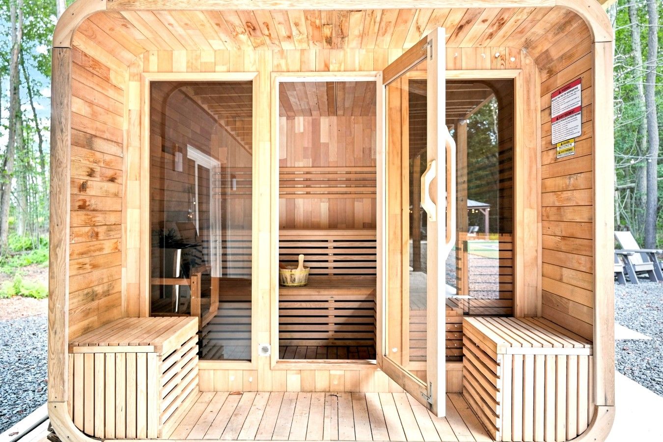 Uma sauna de madeira com bancos e assento, uma porta e uma janela.