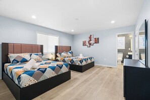 A bedroom with two beds, a flat-screen TV, and a bathroom visible through an open door. - 6 Masters, 8 Bath, Indoor Pool, Pickle Ball Ct, Hot tub, Sauna, Big Game Room (Long Pond)
