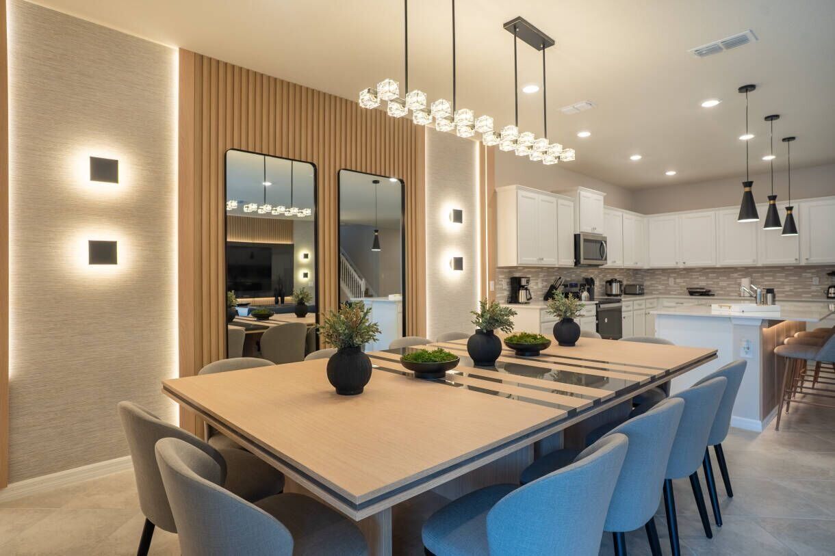 Une cuisine moderne avec des meubles blancs, un îlot central et des luminaires suspendus.