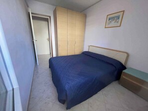 Un dormitorio con una cama, un armario y una mesita de noche.