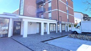 Um edifício moderno com fachada de tijolos, janelas amplas e área de entrada coberta.