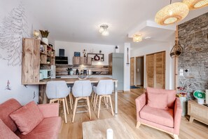 Un salon moderne avec un coin repas, des meubles en bois et une cuisine en arrière-plan.