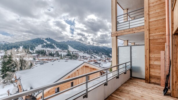 Un balcón de madera con vista a un pueblo nevado.