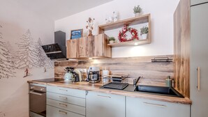 Una cocina moderna con encimera de madera, electrodomésticos integrados y estanterías decorativas.