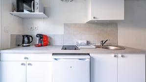 Eine moderne Küche mit weißen Schränken, einer eingebauten Mikrowelle, einer Kaffeemaschine, einem Wasserkocher und einem Spülbecken.