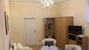 Un salon comprenant un canapé, deux fauteuils, une petite table, un téléviseur et un meuble en bois doté de portes en verre.