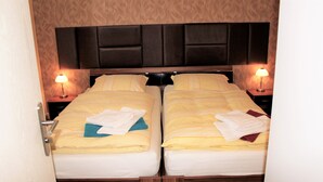 Un lit double avec une tête de lit, deux tables de chevet avec des lampes et des serviettes sur les lits.