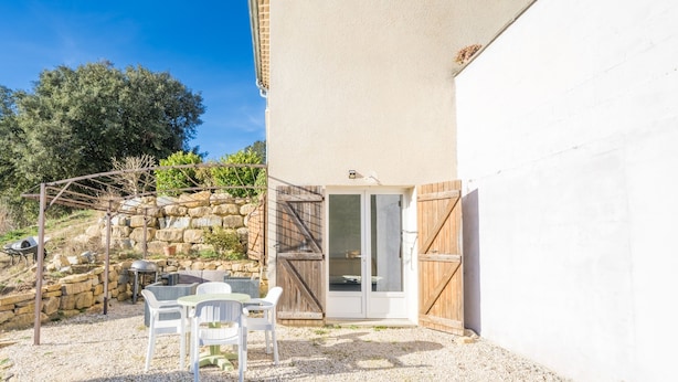 Eine Terrasse mit Tisch und Stühlen, eine Steinmauer und ein Holztor.