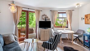 En moderne stue med sofa, stribet lænestol, rundt bord, fjernsyn og en globe på et skab.